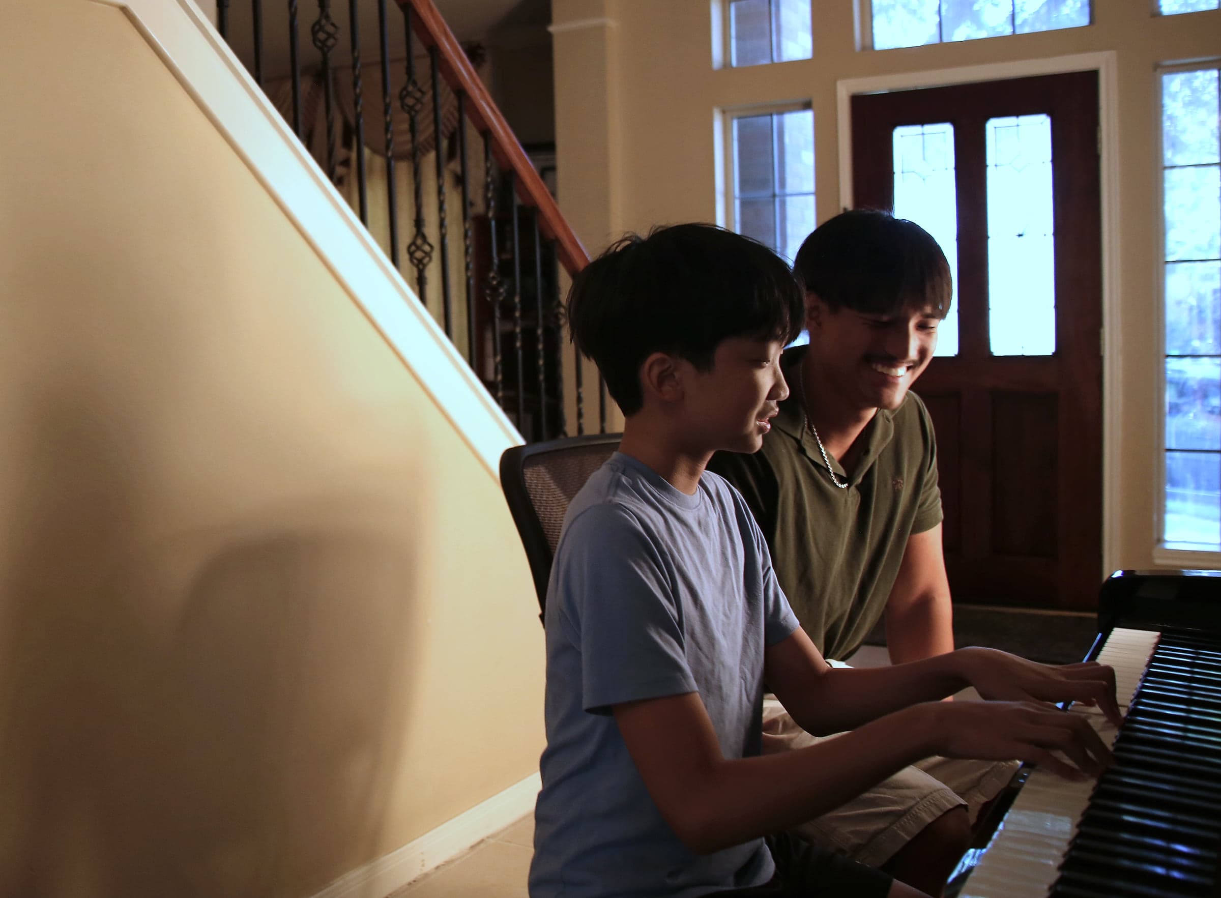 Preston leaning in to watch a student play, both laughing