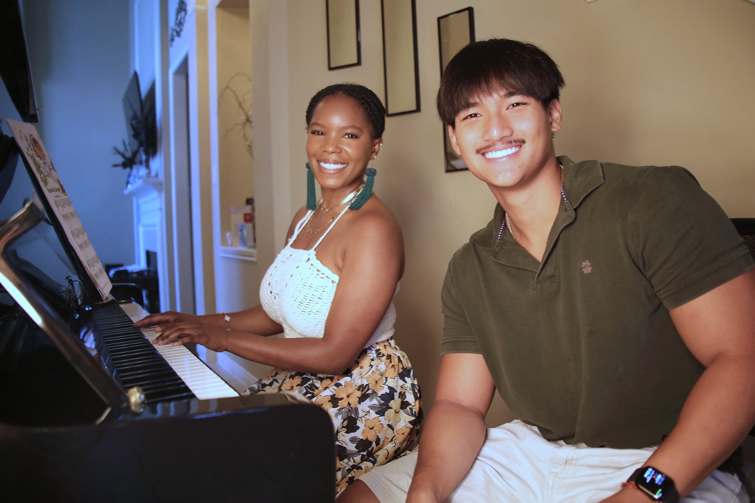 An adult student and Preston at the piano, smiling at the camera