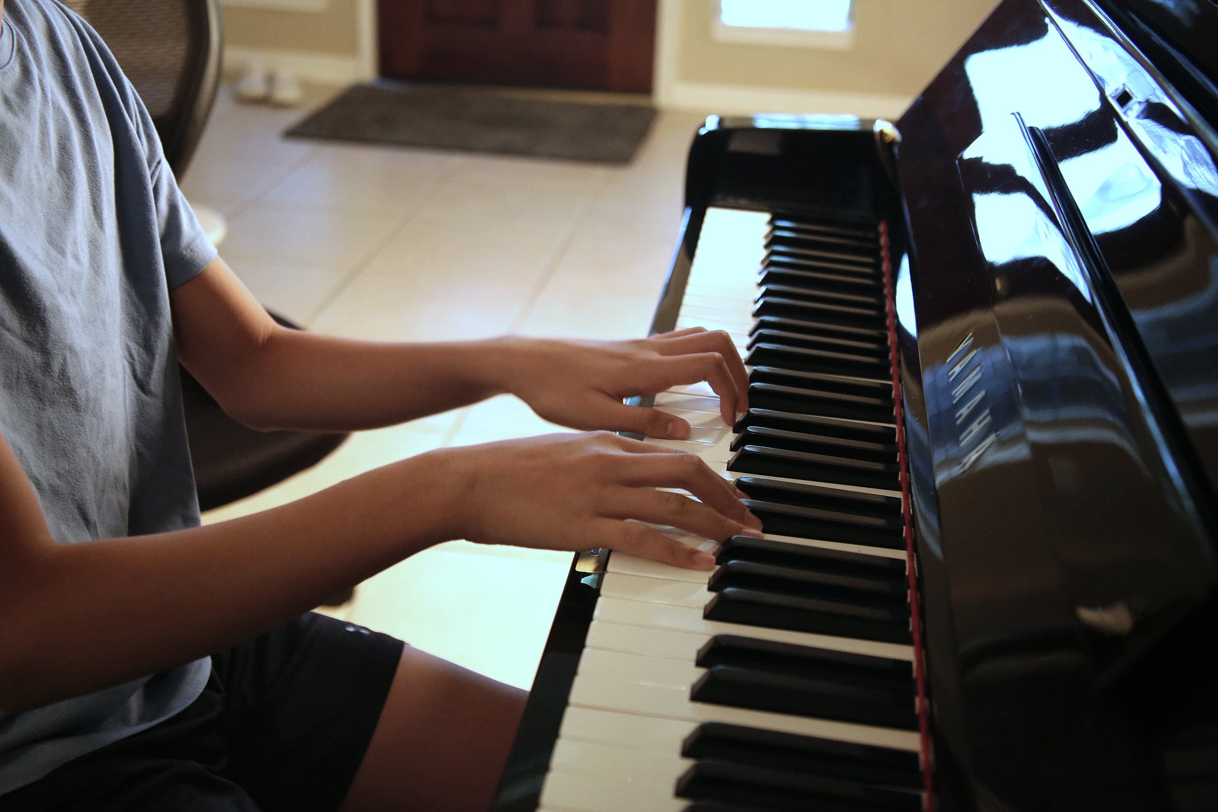 A student's hands spread across the keys of a Yamaha upright piano
