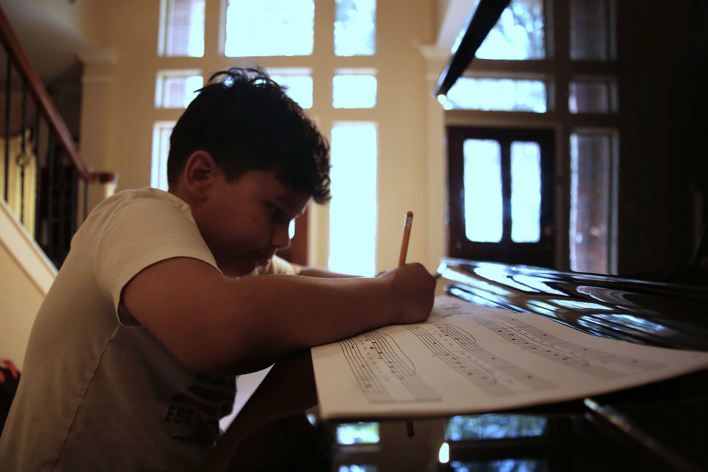A student marking up sheet music with a pencil at the piano